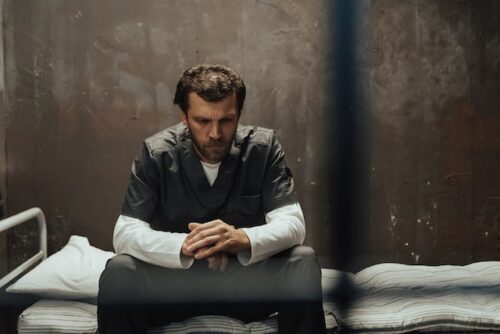 man sitting alone in jail cell