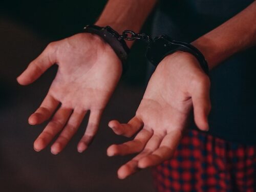 man with hands in handcuffs palms facing up