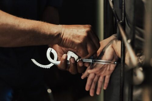 person handcuffed in jail cell
