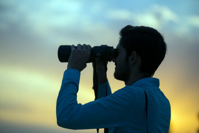 man looking through binoculars