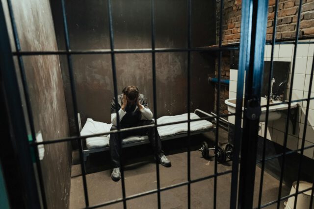 man sitting in jail cell